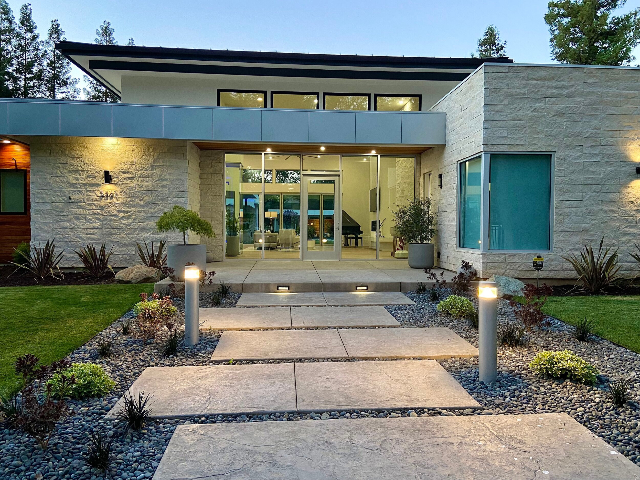 Landscaped approach and broad glass entry framed by pale masonry