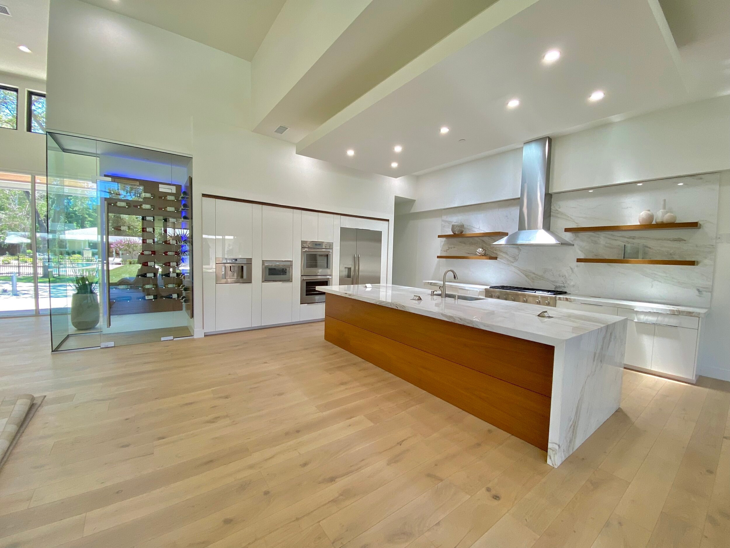 Modern kitchen with a stone island, warm wood panels and floating shelves
