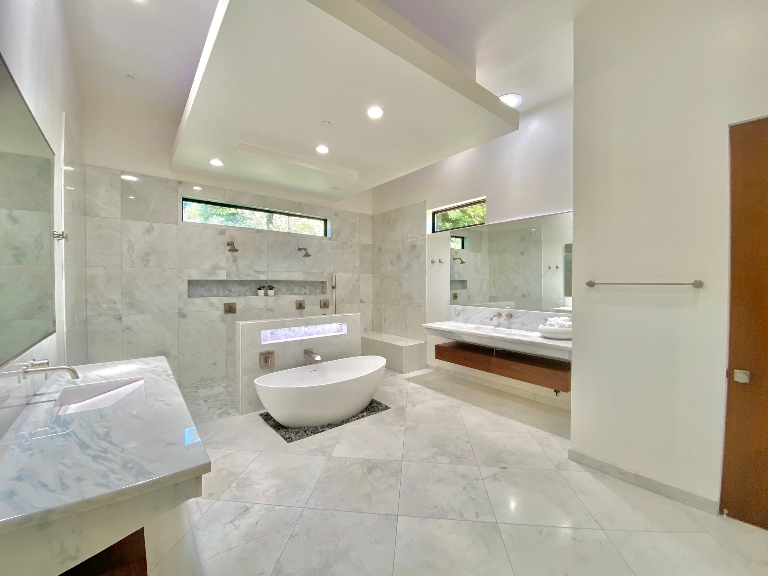 Primary bathroom with a freestanding tub, stone surfaces and a floating vanity