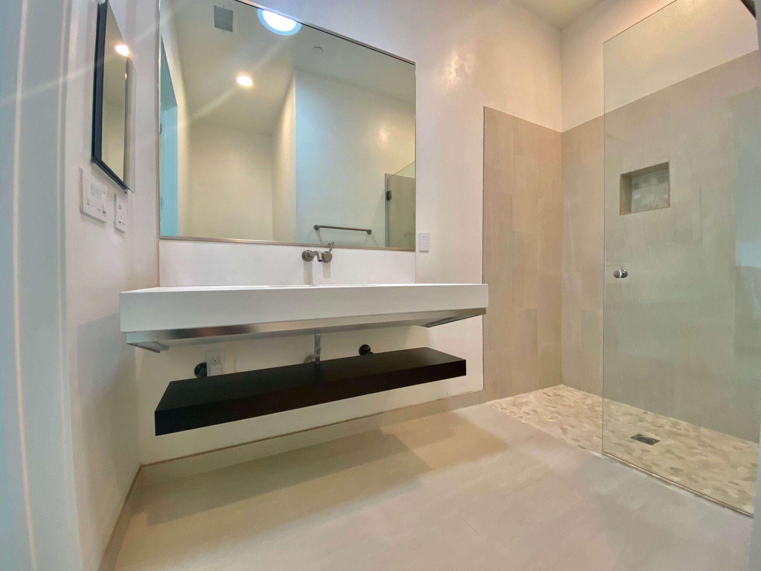 Bathroom with a floating vanity, broad mirror and walk-in shower