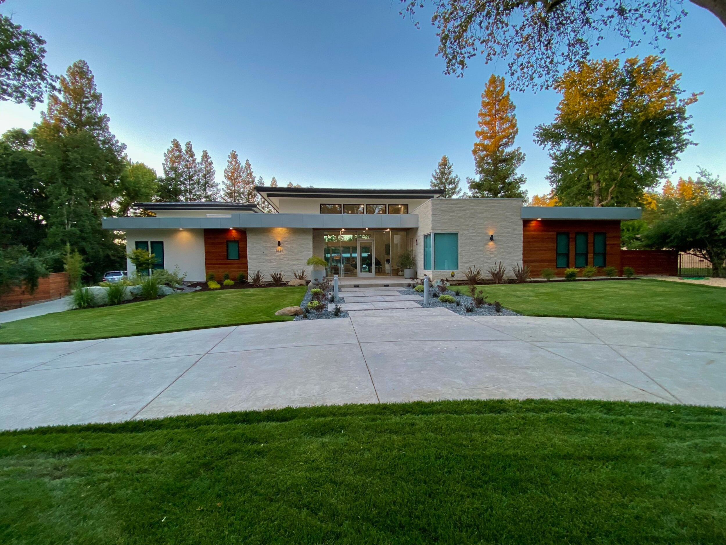Wide evening view of the Arden Project with illuminated entry and mature trees