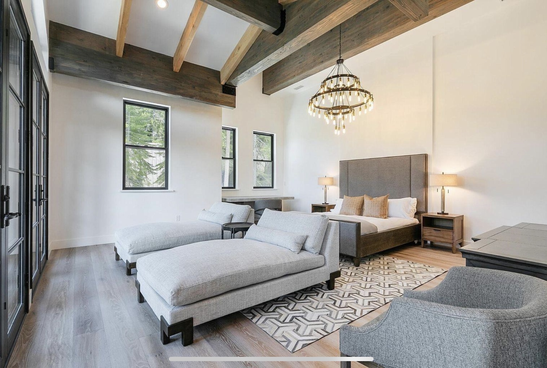 Primary bedroom with exposed ceiling beams, a chandelier and a window-side sitting area