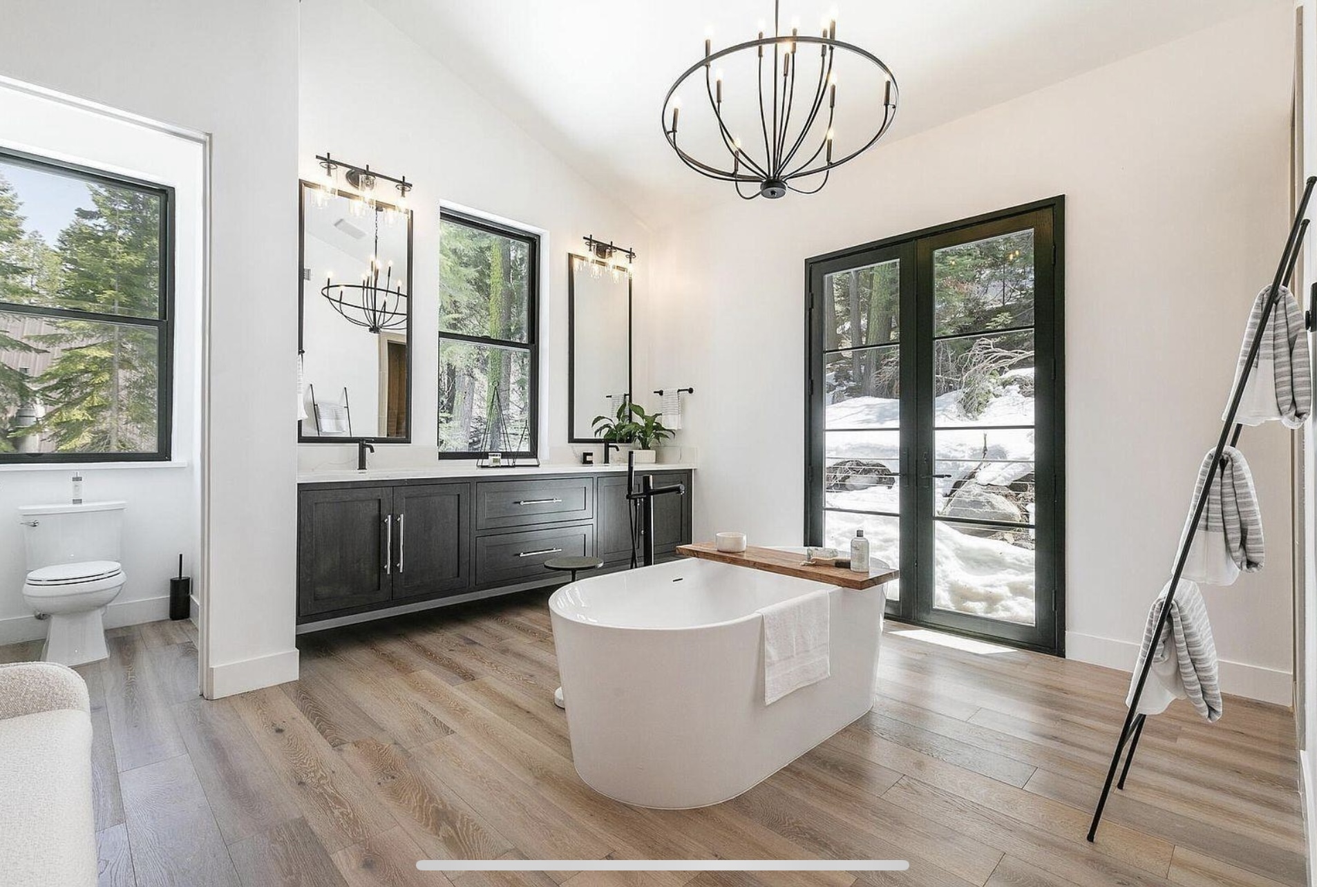 Primary bathroom with a freestanding tub, dark vanity and tall windows