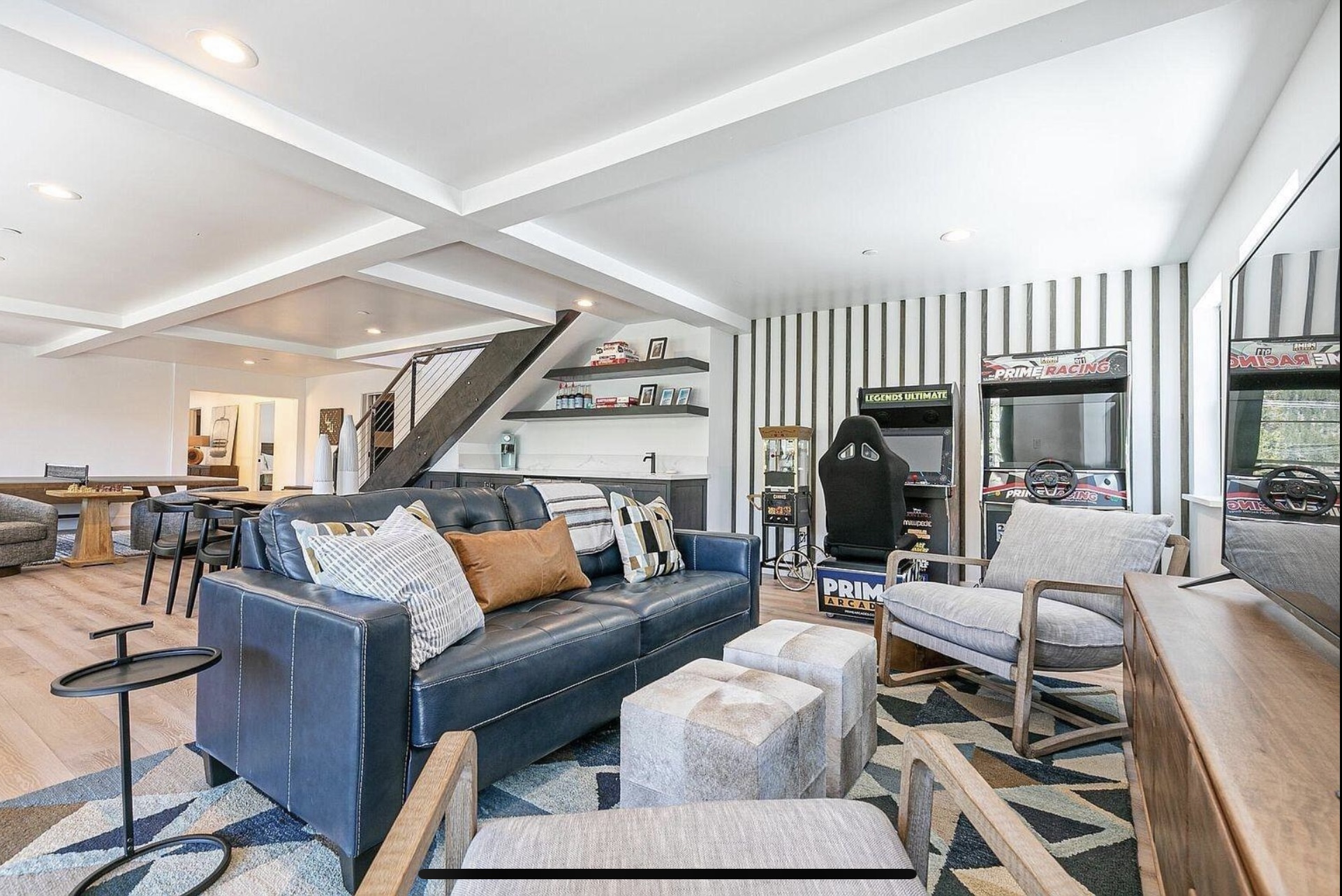 Lower-level recreation room with lounge seating, game space and an open stair