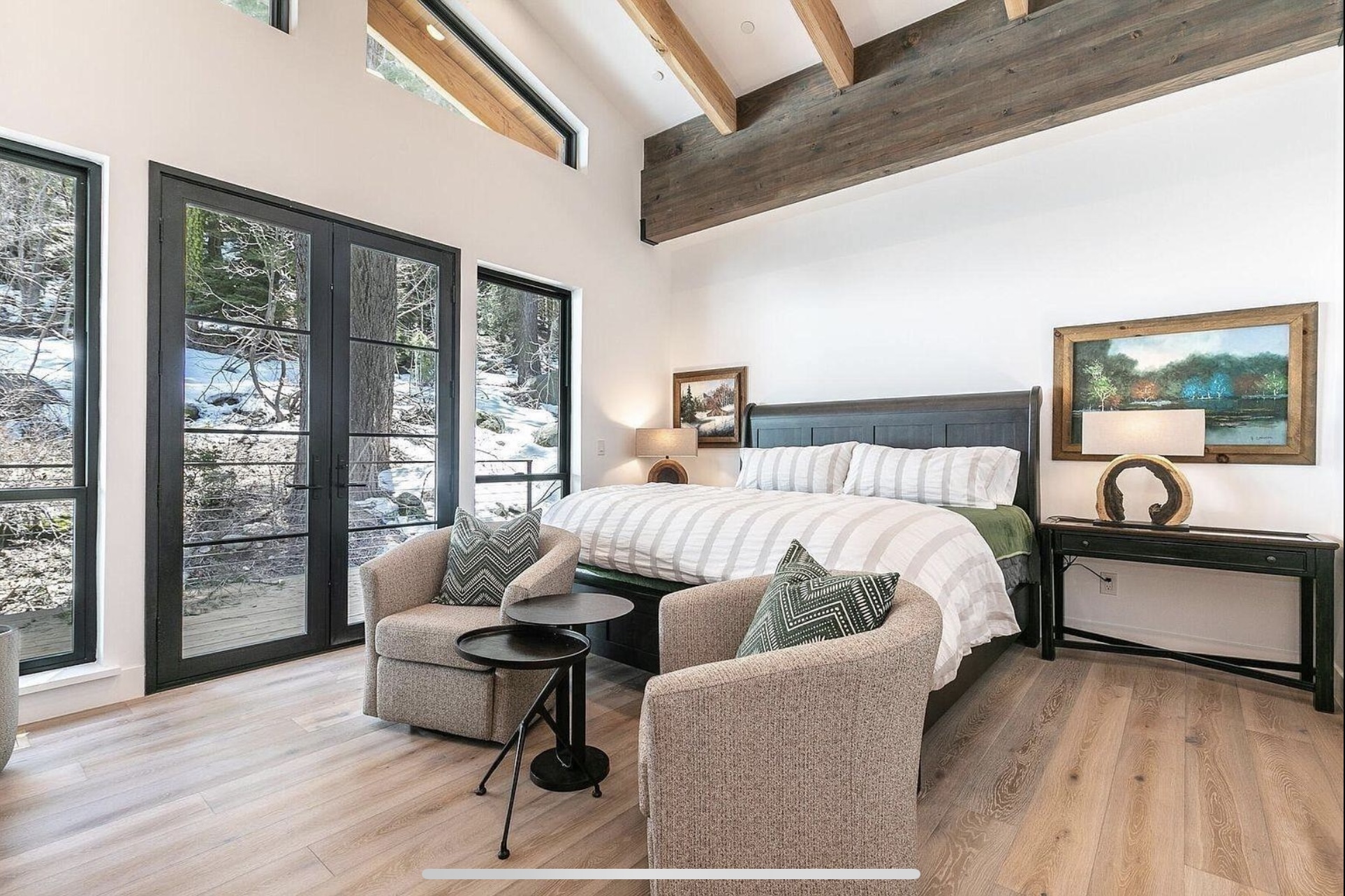 Bedroom retreat with exposed beams, tall windows and a pair of upholstered chairs