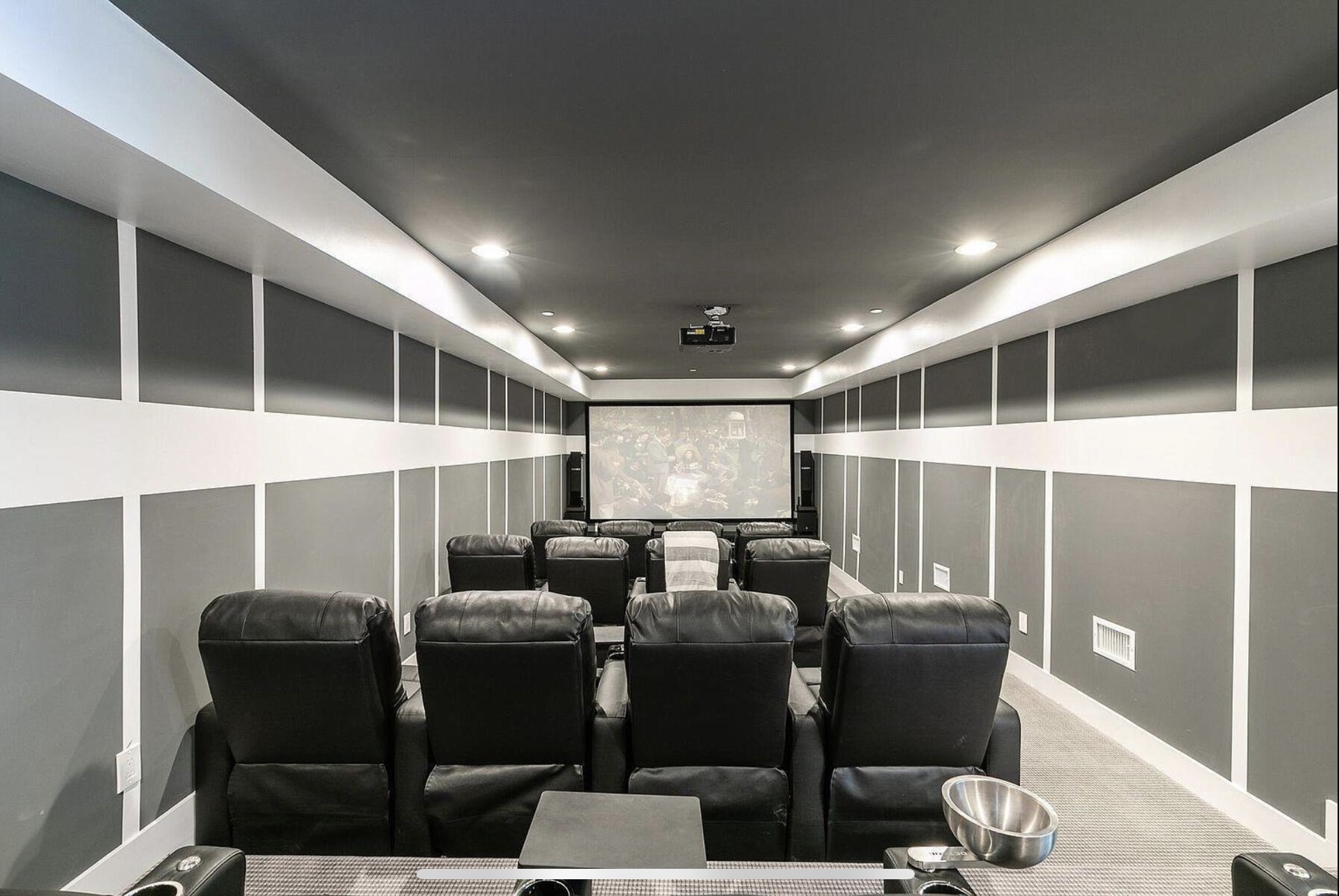 Home theater with tiered reclining seats and dark paneled walls