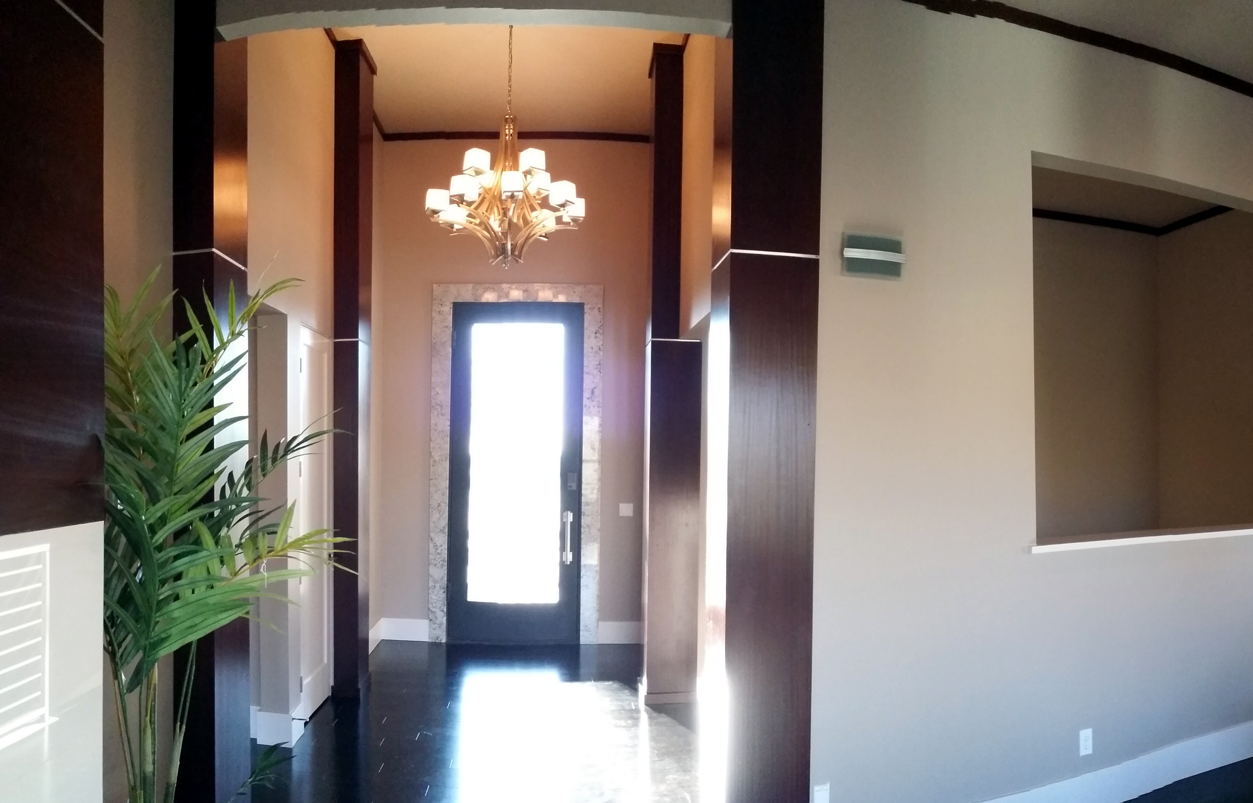 Tall entry with warm wood trim and a chandelier