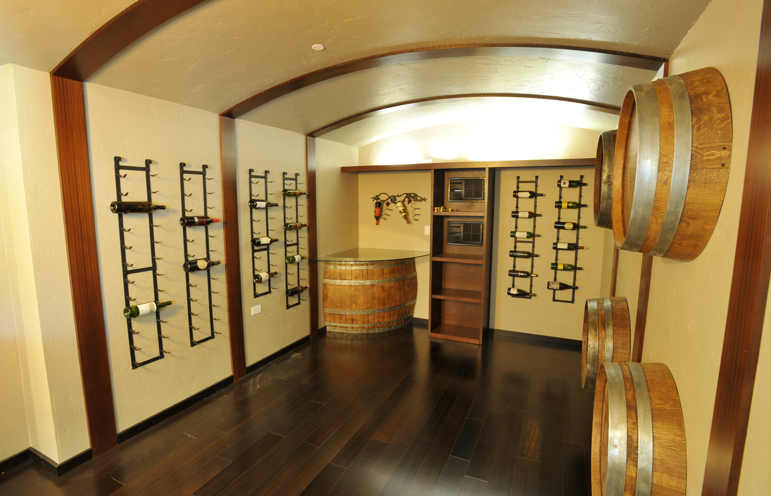 Wine room with dark wood floors, bottle racks and barrel details