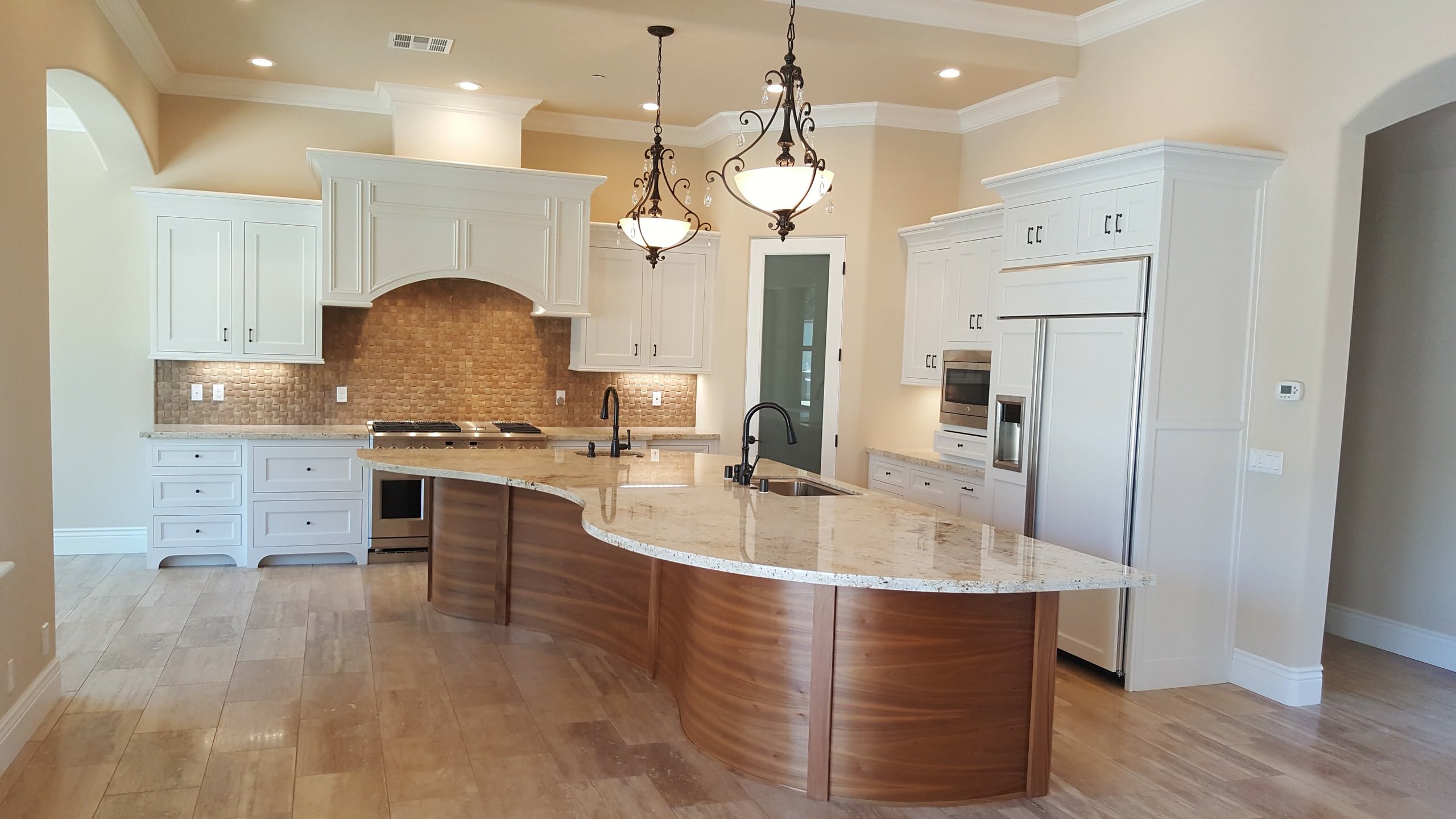 Curved stone kitchen island with warm wood cabinetry