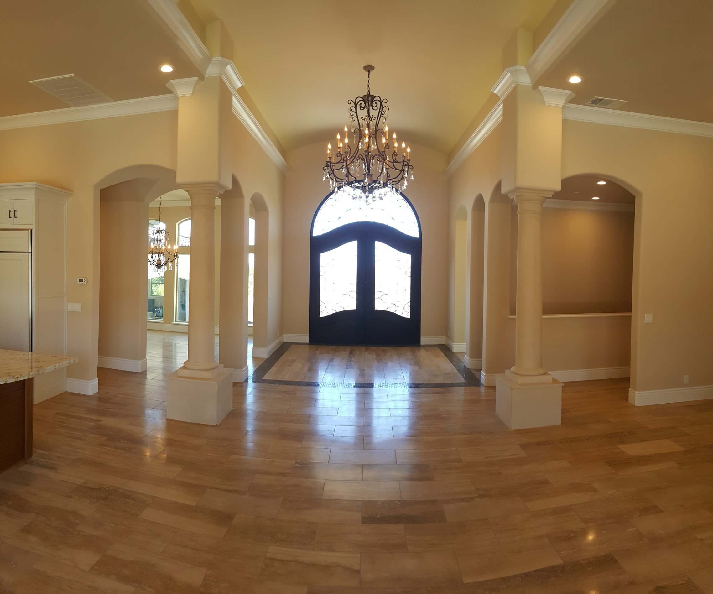 Entry hall with a chandelier, columns and warm stone flooring