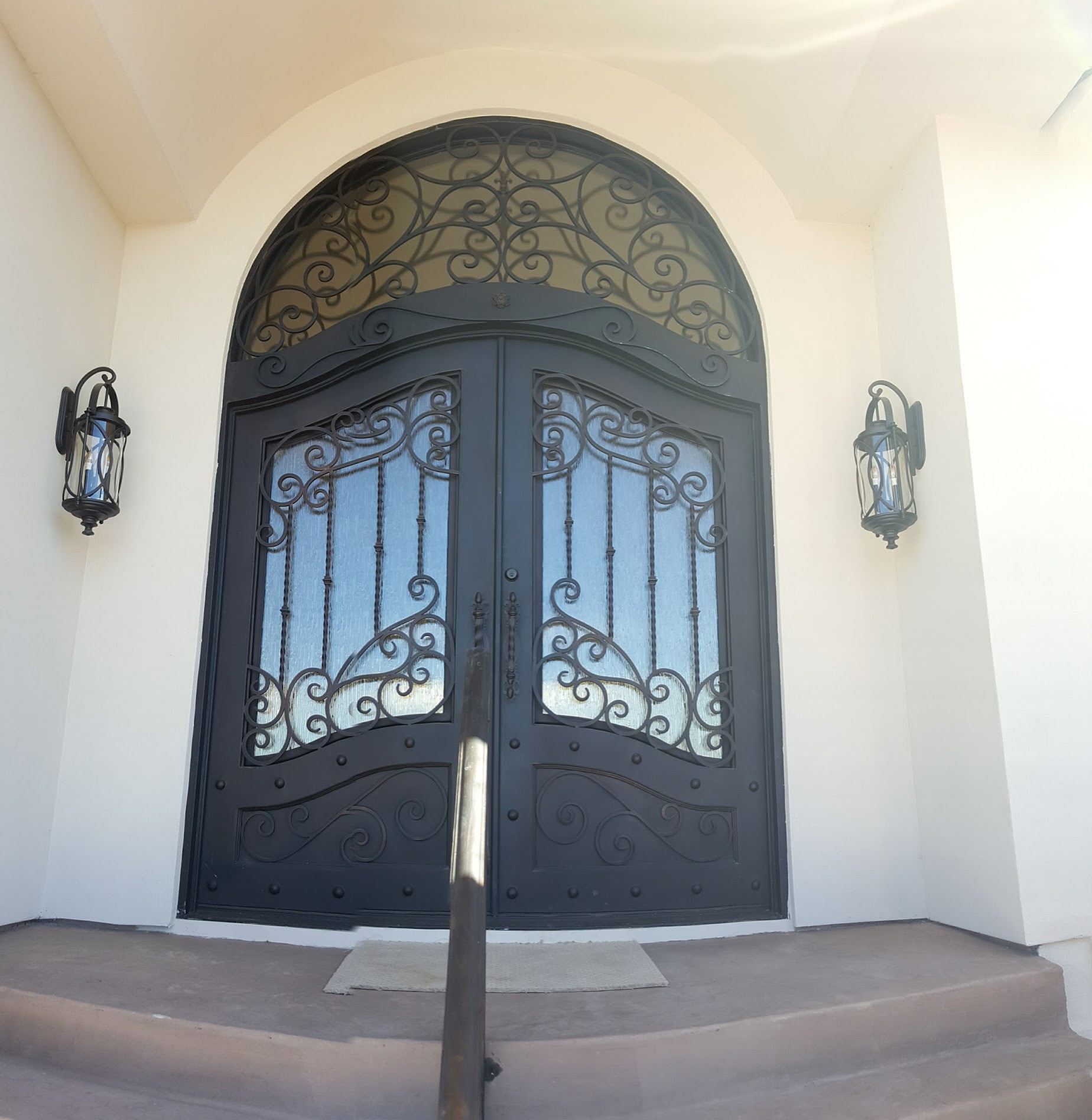 Arched double entry doors with ornate ironwork