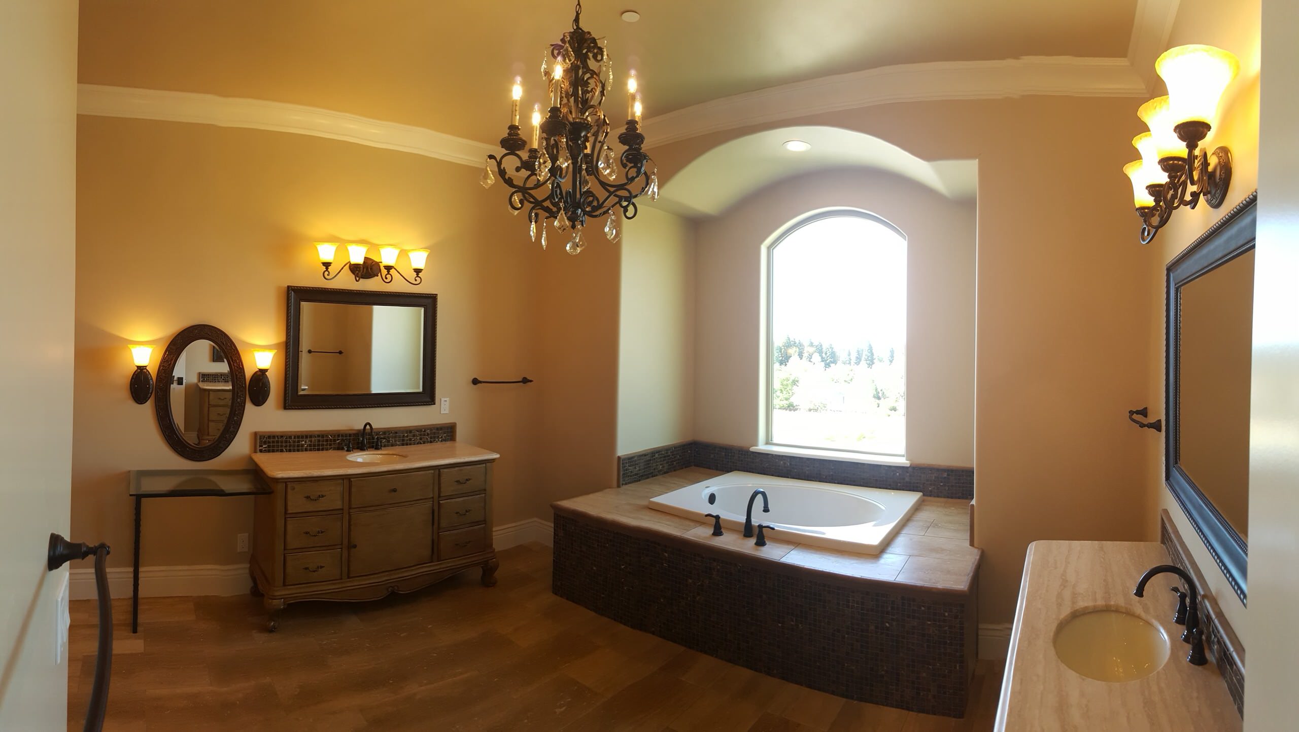 Bathroom with a soaking tub, arched window and ornate lighting