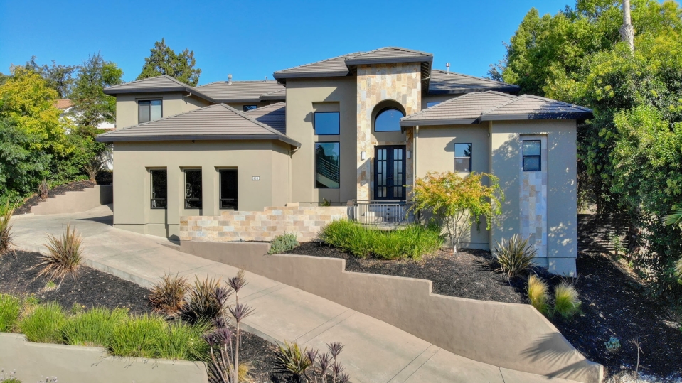Front elevation framed by mature trees and landscaped terraces
