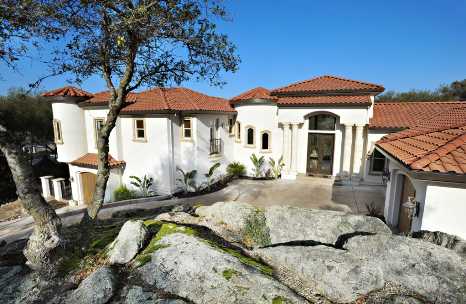 Stonebridge Residence with pale stucco, tiled roofs and a natural rock landscape